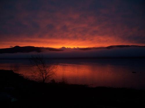a sunset over a body of water with a cloudcoveredermottermott at Maggie's in Inveraray