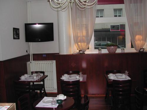 comedor con mesas y sillas y TV en Hôtel Alexandra, en Boulogne-sur-Mer