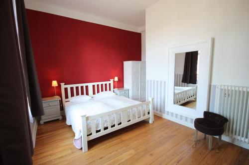 a bedroom with a white bed and a red wall at Strandperle Lieblingsplatz Hotel in Travemünde
