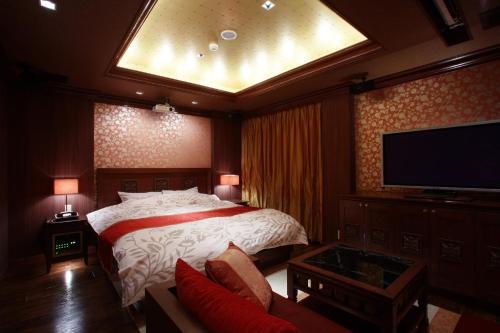 a bedroom with a bed and a flat screen tv at Hotel Water Gate Tokuyama adult only in Shunan