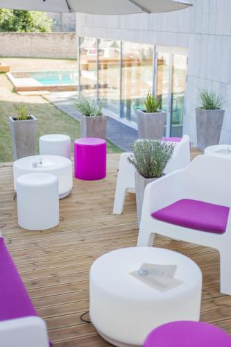 a patio with white tables and purple chairs at Johan Suites & Spa in Kuressaare
