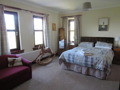 een slaapkamer met een bed, een stoel en ramen bij The Greannan Bed & Breakfast in Blackwaterfoot