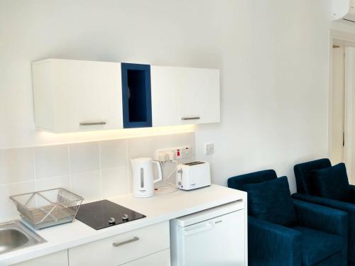 a kitchen with white cabinets and a blue chair at Olosuites in Limassol