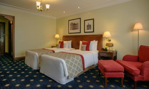 a hotel room with two beds and a red chair at Sarova Stanley in Nairobi