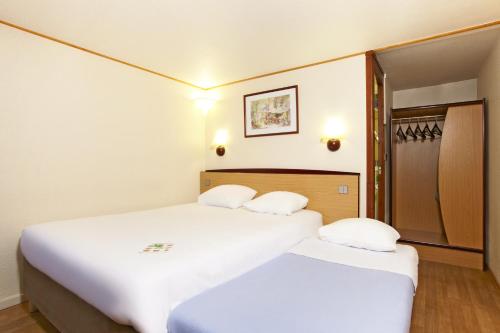 2 bedden in een hotelkamer met witte lakens bij Campanile Cholet in Cholet