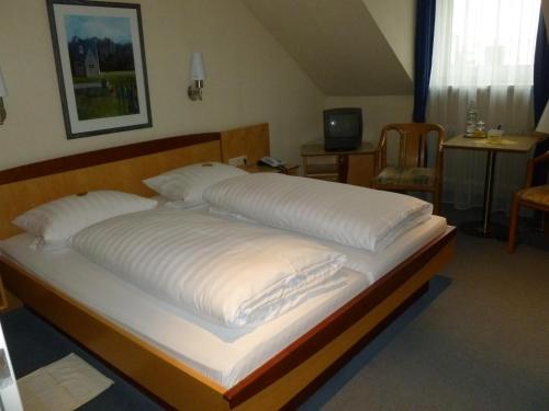 ミュンヘンにあるホテル ハウザー アン デア ウニヴェルシテットの大型ベッド(白いシーツ、枕付)