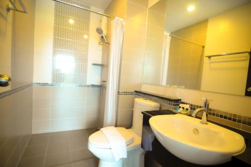 a bathroom with a sink and a toilet and a mirror at The Sila Hotel in Si Racha