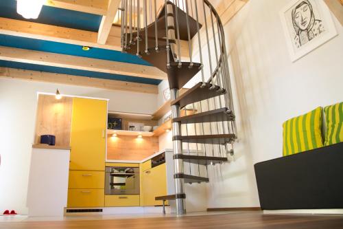 a spiral staircase in a kitchen with yellow cabinets at Südalpen Lofts in Bleiburg