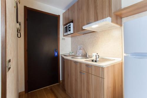 uma pequena cozinha com um lavatório e uma porta preta em Residence Desenzano em Milão