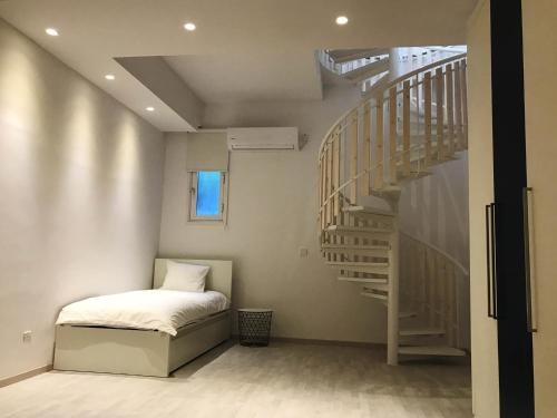 a bedroom with a bed and a spiral staircase at Olosuites in Limassol