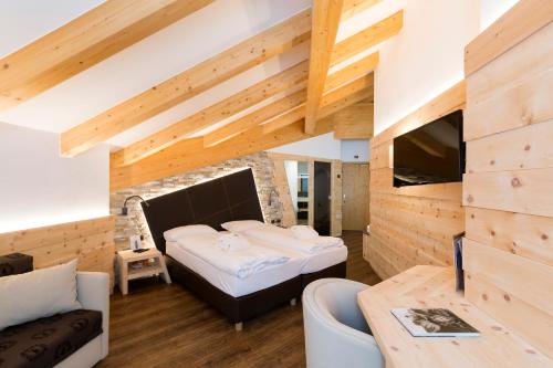 a bedroom with a bed in a room with wooden walls at Wellness Hotel Lupo Bianco in Canazei