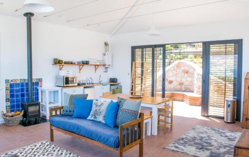a living room with a blue couch and a table at Modern Beach Apartment in Kalk Bay