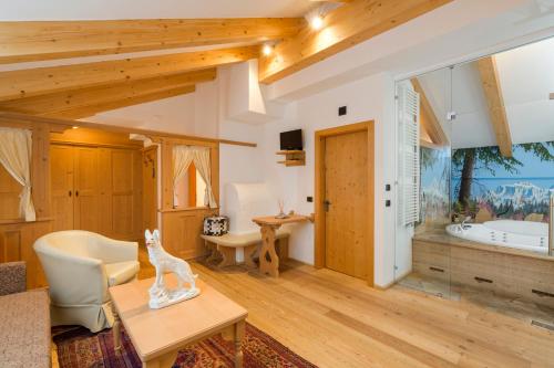 a living room with wooden ceilings and a room with a tub at Wellness Hotel Lupo Bianco in Canazei