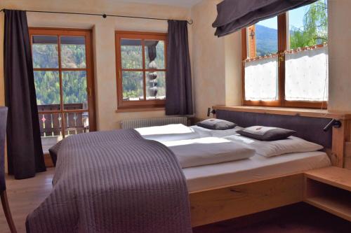 1 dormitorio con 1 cama y 2 ventanas en Apartments Moarhof, en Velturno