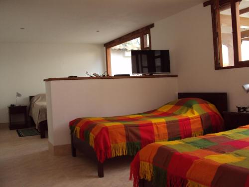 a bedroom with two beds and a tv on the wall at Casa Leo in Villa de Leyva