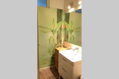 a bathroom with a sink and a large plant mural on the wall at Apartament Monika in Sopot