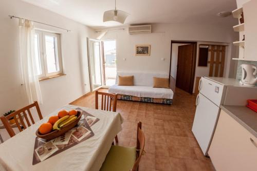 una cucina e un soggiorno con tavolo e frutta di Apartments Nenad & Marija a Pag