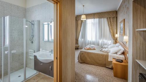 a bathroom with a bed and a sink and a shower at Hotel Sorriso in Lucera