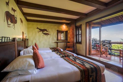 1 dormitorio con 1 cama grande y balcón en Ngorongoro Serena Safari Lodge, en Ngorongoro