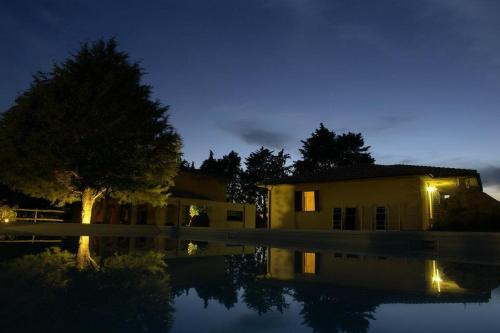 a house with a reflection in the water at night at Agriturismo Cavallin Del Bufalo in Manciano