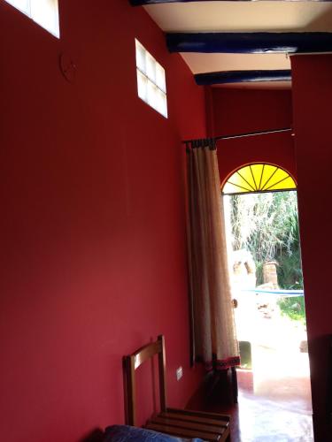 a bedroom with a red wall and two windows at La Casita de mi Abuela in Mancos