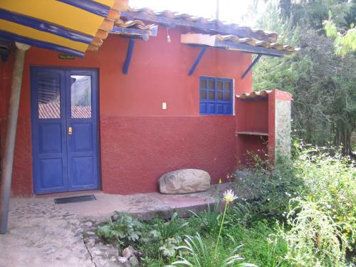 a red house with a blue door and a rock at La Casita de mi Abuela in Mancos