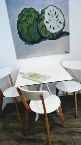 a table and chairs and a painting of a cabbage at The Marketplace by Storytellers in Funchal
