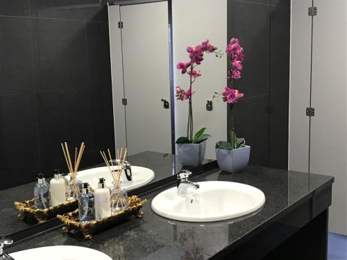 two sinks in a bathroom with a mirror and flowers at Luna Hotel Turismo in Abrantes
