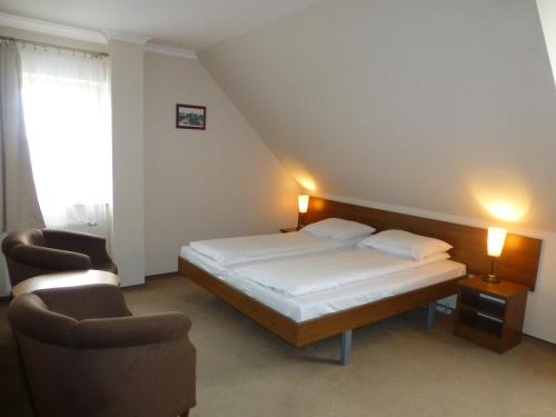 a bedroom with a bed and two chairs in it at Hotel Cesarski - Kaiserhof in Giżycko