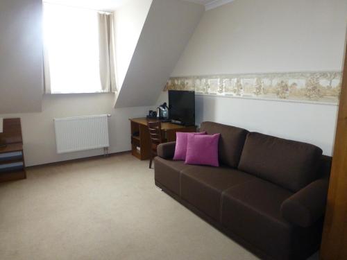 a living room with a brown couch and a pink pillow at Hotel Cesarski - Kaiserhof in Giżycko