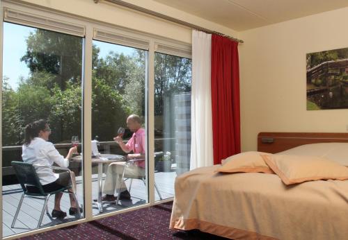 dwie osoby siedzą przy stole w sypialni w obiekcie Hotel de Harmonie w mieście Giethoorn