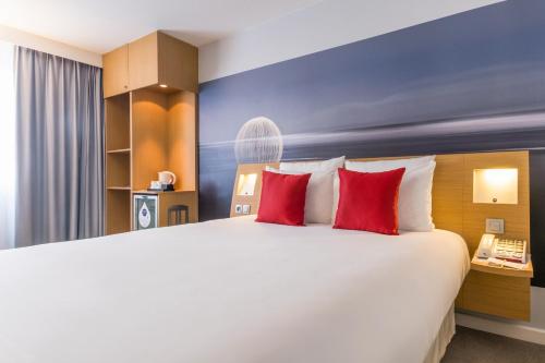 a bedroom with a large bed with red pillows at Novotel Strasbourg Centre Halles in Strasbourg