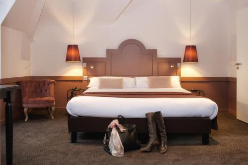 Un dormitorio con una cama grande con botas. en La Maison des Armateurs, en Saint-Malo