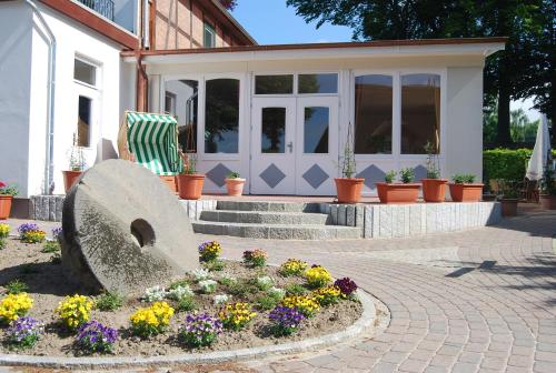 a house with a flower garden in front of it at Flair Landhotel Strengliner Mühle in Pronstorf