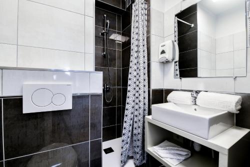 a white bathroom with a sink and a shower at Hôtel Le Rupella in La Rochelle