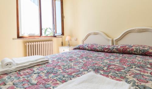 a bedroom with a bed with a floral bedspread and two windows at Camere Mariella in Bastia Umbra