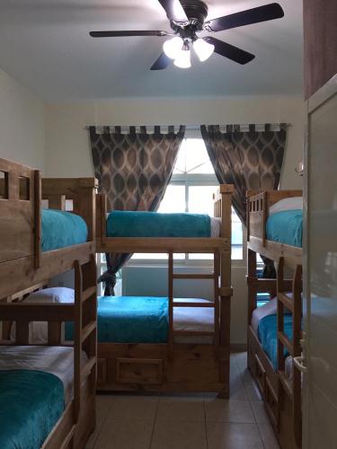 a room with four bunk beds and a ceiling fan at Hostal Bucerias in Bucerías