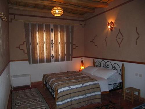 a bedroom with a bed in the corner of a room at Auberge des peupliers Café Restaurant in Akhendachou nʼAït Ouffi