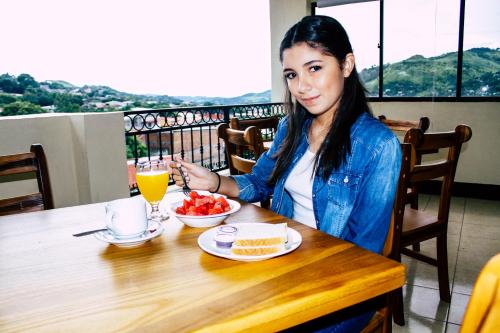 una donna seduta a un tavolo con un piatto di cibo di Hotel Palmeras de Elim a Matagalpa