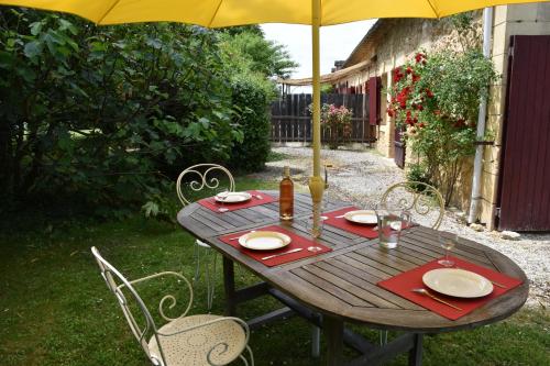 une table en bois avec des chaises et un parasol dans l'établissement Du vert & du bon air - Linge maison inclus - Parking Privé Gratuit - Centre ville Bergerac 10mn - Domaine Bellevue Cottage en Périgord, à Lembras