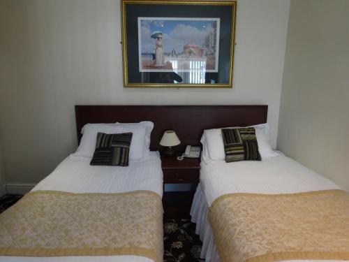 two beds in a hotel room with a picture on the wall at Waverley Hotel in Workington