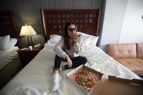 a woman sitting on a bed with a box of food at La Copa Inn Beach Hotel in South Padre Island