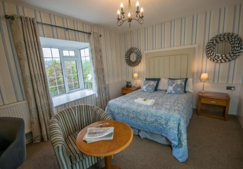 a bedroom with a bed and a chair and a table at Old Kings Arms Hotel in Pembroke