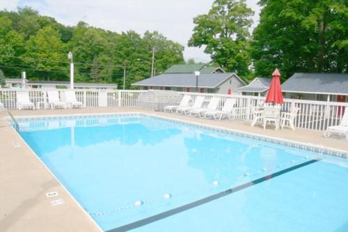 a large swimming pool with chairs and a red umbrella at Barberry Court Motel &Cabins in Lake George