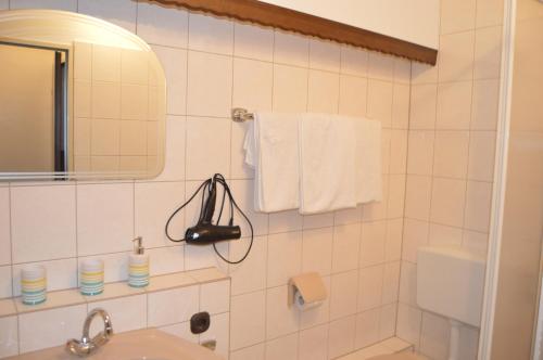 a white tiled bathroom with a sink and a mirror at Hotel Zur Rose in Bad Karlshafen