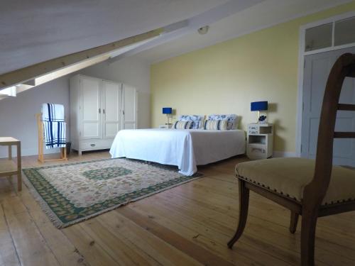 um quarto com uma cama, uma cadeira e uma mesa em Casa Coimbra em Coimbra