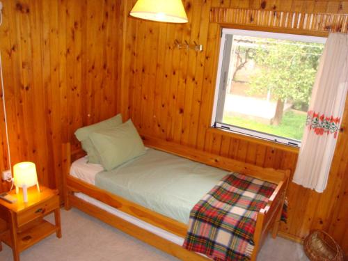 a small bed in a wooden room with a window at Three Bedroom Country House in Magoúla