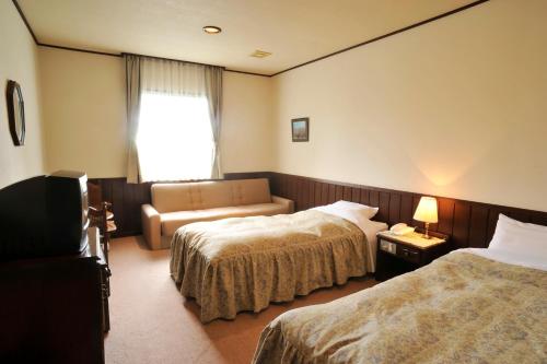 Habitación de hotel con 2 camas y sofá en Pension Totem Pole, en Ito