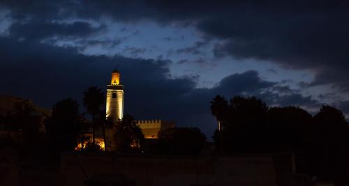 a building with a lit up tower at night at Riad Al Fassia Palace in Fès