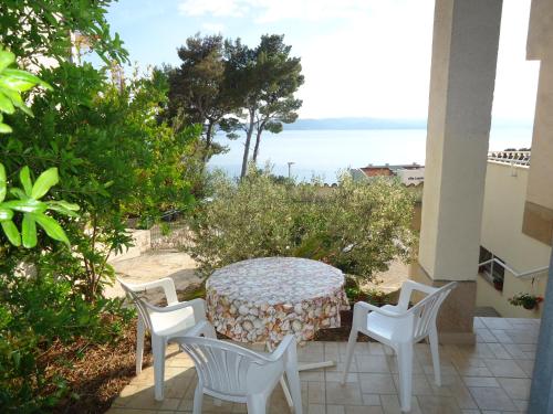 un patio con mesa, sillas y el océano en Apartments Marica, en Brela